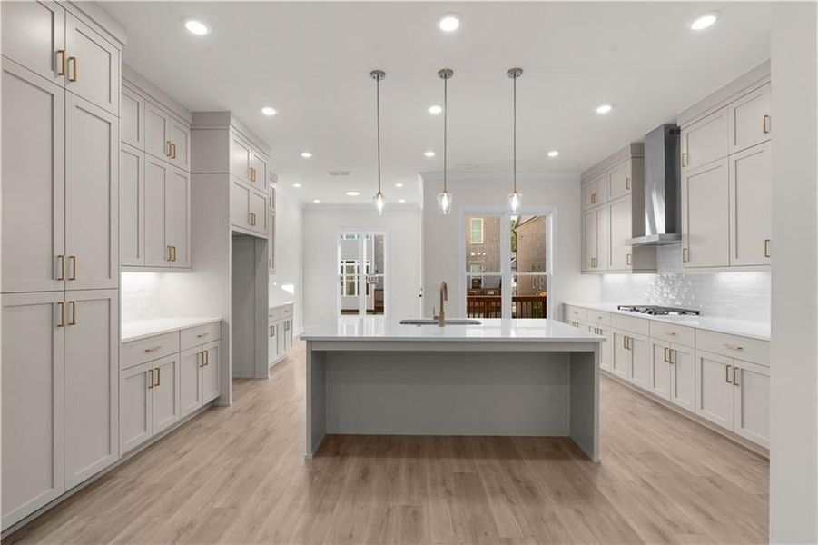 Kitchen featuring pendant lighting, tasteful backsplash, light wood-type flooring, light stone counters, and recessed lighting