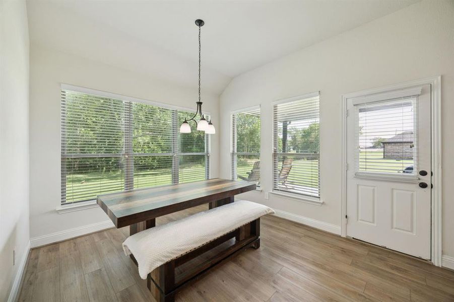 Dining space with healthy amount of natural light, lofted ceiling, and a chandelier.