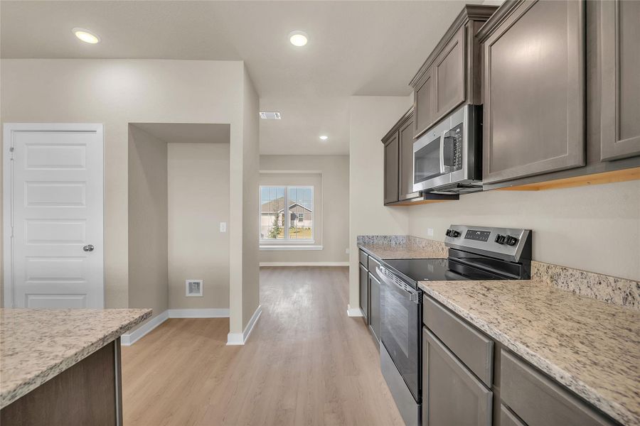 Kitchen featuring stainless steel appliances, light stone countertops, recessed lighting, and light wood-style floors