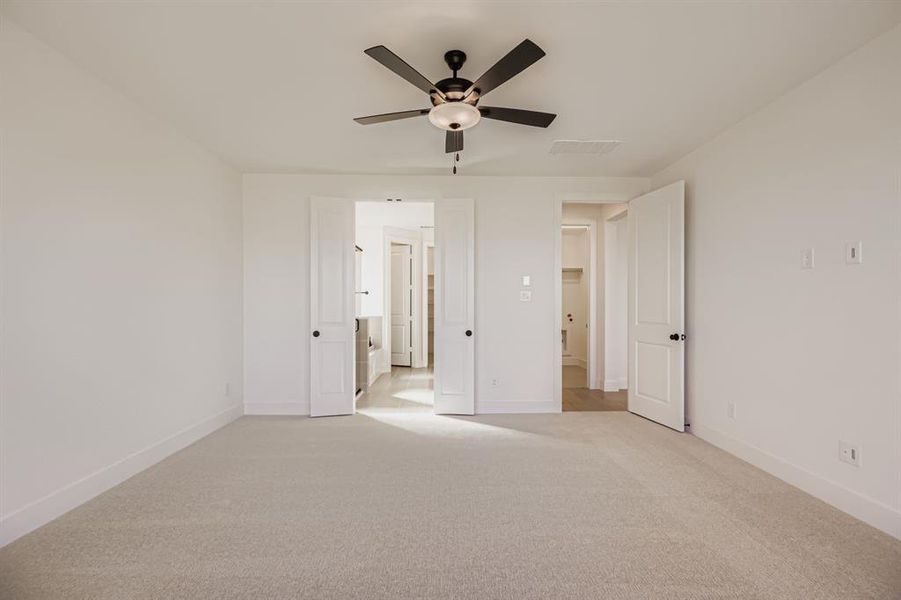 Unfurnished bedroom featuring carpet, a ceiling fan, and ensuite bathroom
