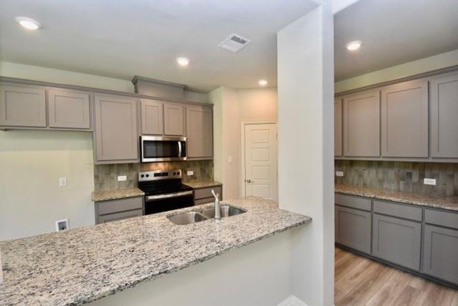 Kitchen featuring stainless steel appliances, gray cabinetry, light stone countertops, and recessed lighting