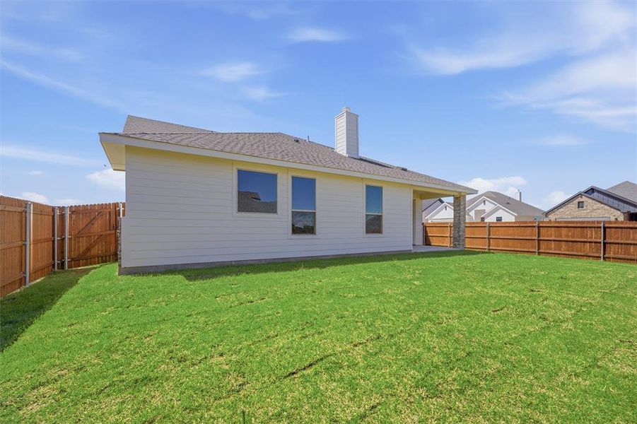 Back of house featuring a chimney, a fenced backyard, a shingled roof, and a patio