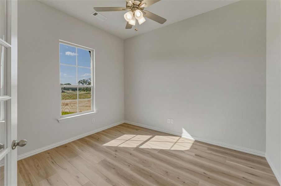 Room featuring wood-finish flooring, a ceiling fan with integrated lighting, and a window with a wide sill Room featuring wood-finish flooring, a ceiling fan with integrated lighting, and a window with a wide sill
