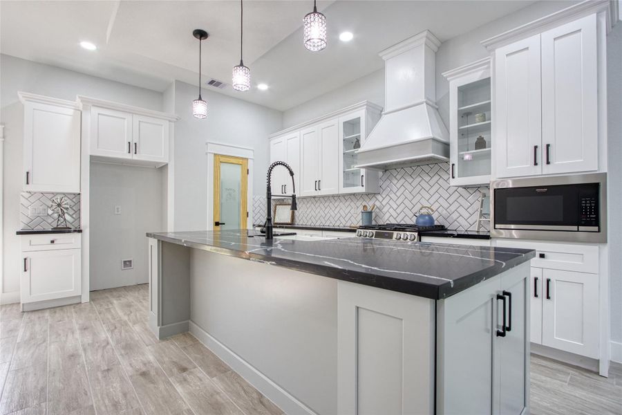 Lots of cabinets, lovely quartz countertops, farmhouse sink and stainless steel appliances complete this modern farmhouse kitchen.