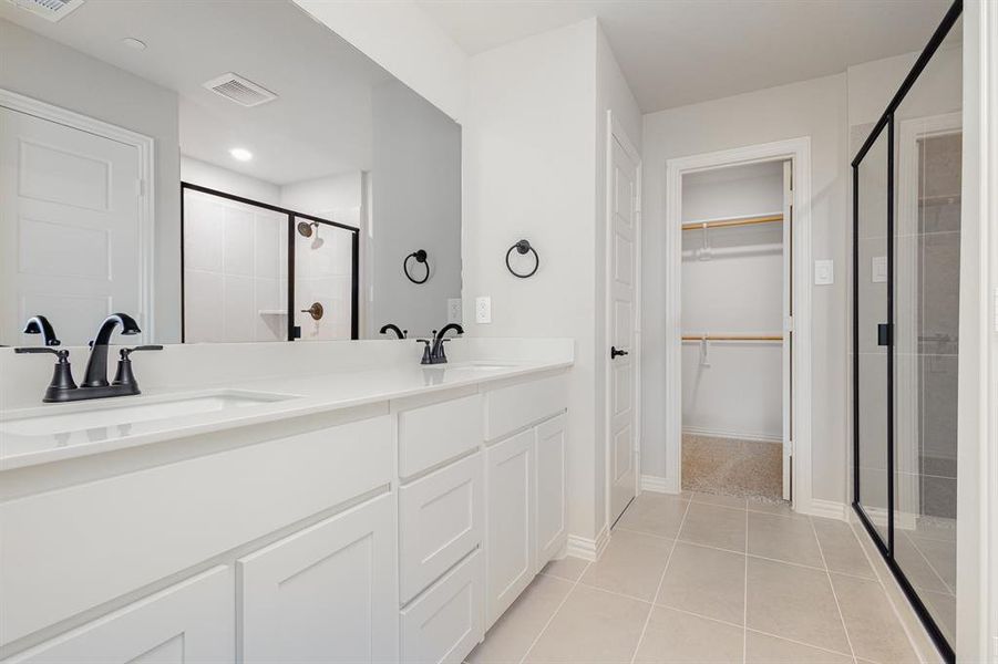 Full bath with a shower stall, a spacious closet, tile patterned flooring, and double vanity