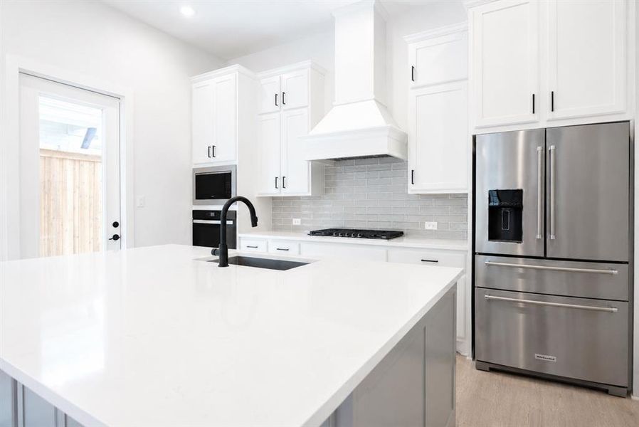 Kitchen island featuring a white countertop with an undermount sink and matte black faucet