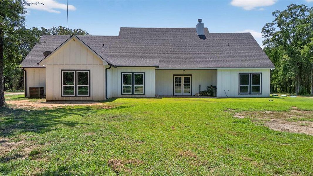 Rear view of house with roof with shingles, a yard, a chimney, and a patio Rear view of house with roof with shingles, a yard, a chimney, and a patio