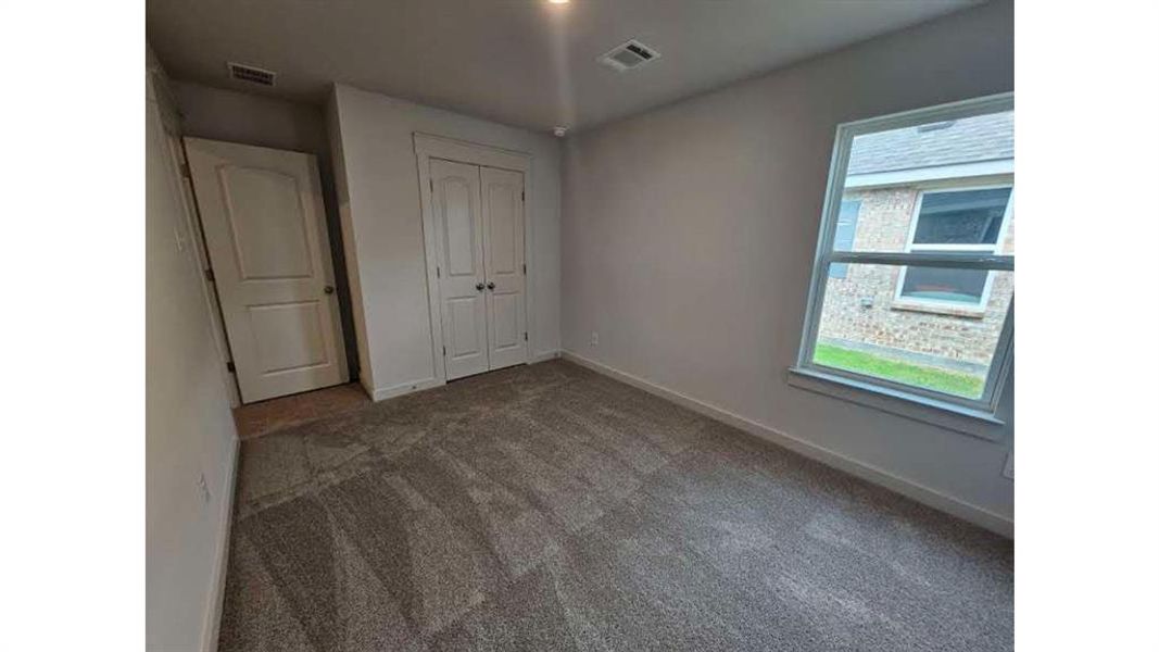 Carpeted interior room with white trim, a double-door closet, a single window, and a white interior door