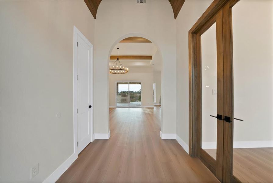 Hall with arched walkways, light wood-type flooring, and a chandelier Hall with arched walkways, light wood-type flooring, and a chandelier