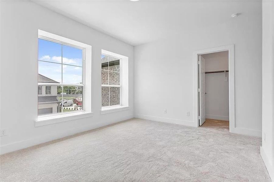 Unfurnished bedroom featuring light carpet, a closet, and a spacious closet