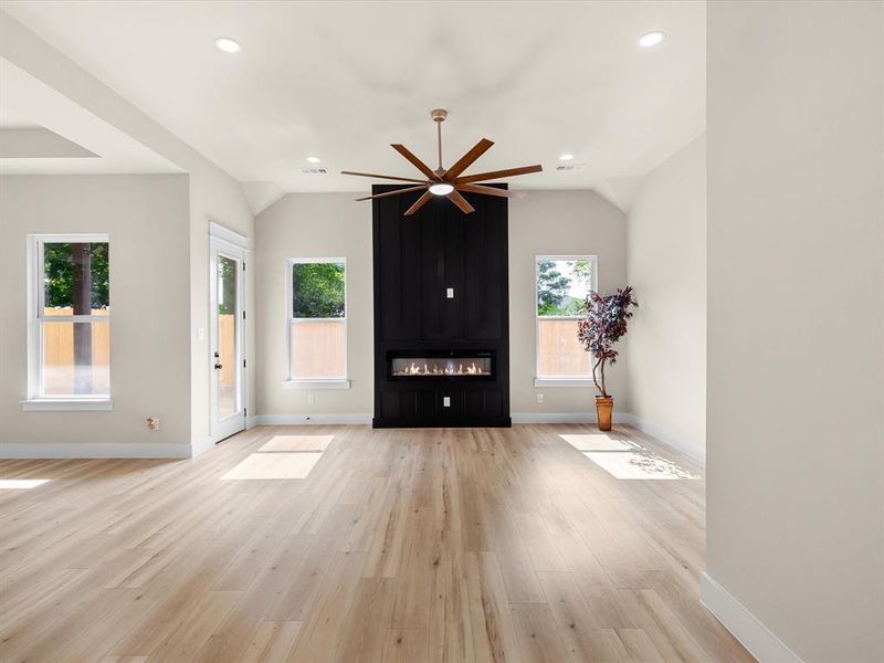 Spacious living area featuring light wood-finish flooring, a contemporary ceiling fan, and recessed lighting