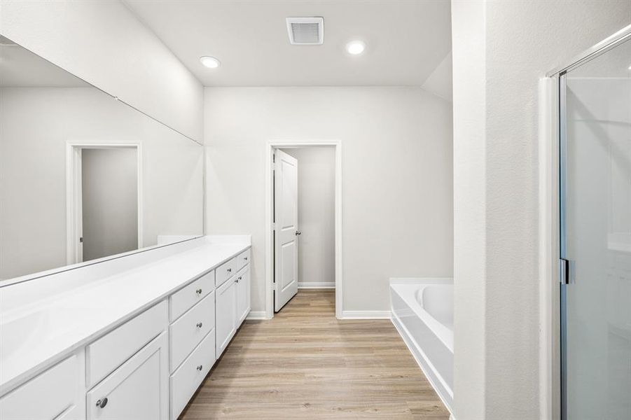 Luxurious primary bathroom with walk-in closets and a separate standing shower.