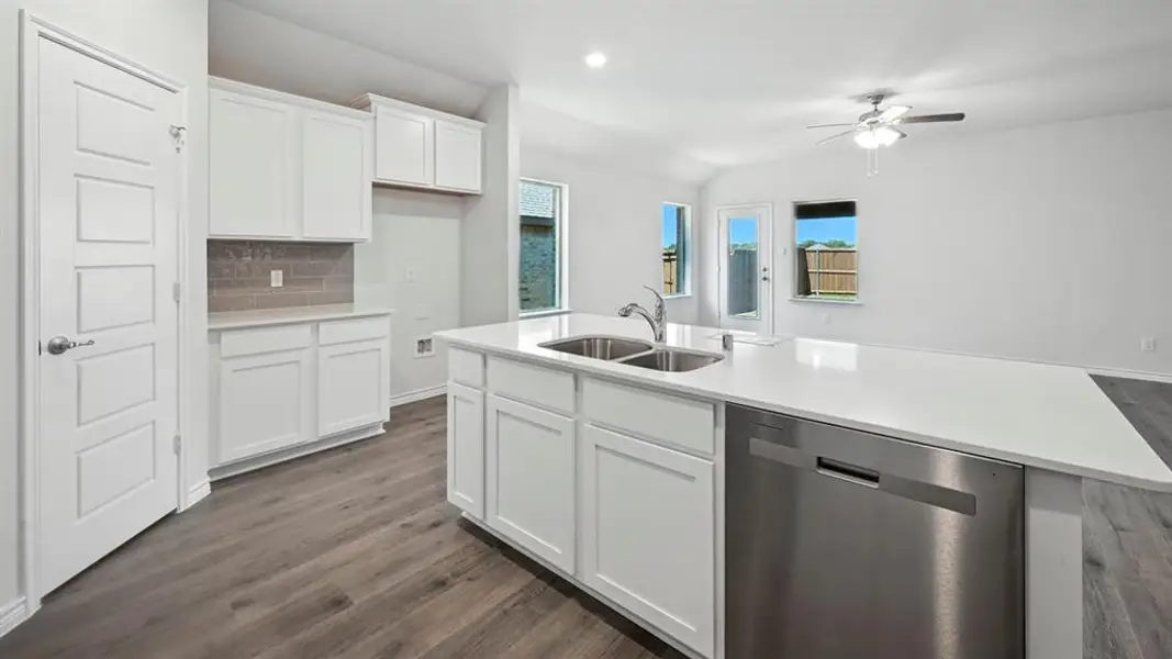 Modern kitchen featuring white cabinetry, a large center island with a double stainless steel sink, stainless steel dishwasher, and wood-finish flooring Modern kitchen featuring white cabinetry, a large center island with a double stainless steel sink, stainless steel dishwasher, and wood-finish flooring
