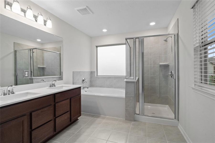 This primary bathroom is definitely move-in ready! Featuring a walk-in shower with tile surround, separate garden tub for soaking after a long day with custom tile detailing, dark stained cabinets with light countertops, spacious walk-in closet with shelving, high ceilings, custom paint, sleek and dark modern finishes.