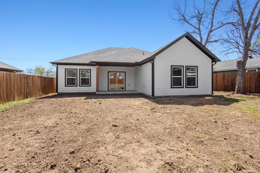 Back of house featuring roof with shingles and a fenced backyard