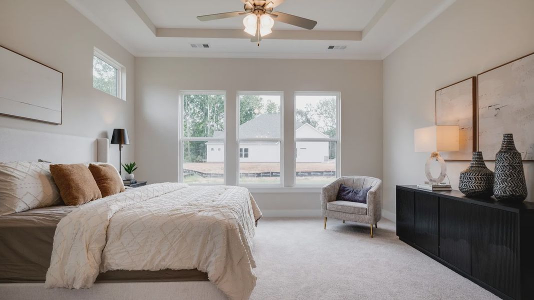Primary bedroom with trey ceilings and sizeable windows connected to bathroom and walk-in closet