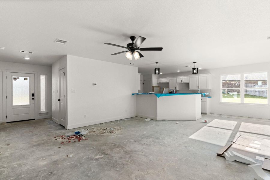 Unfurnished living room featuring ceiling fan and unfinished concrete floors Unfurnished living room featuring ceiling fan and unfinished concrete floors