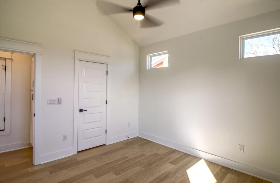Spare bedroom with vaulted ceiling, ceiling fan, and light wood-style floors