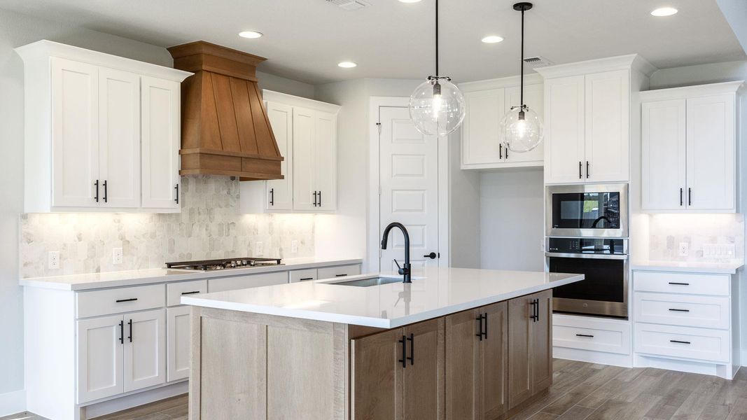 Kitchen with appliances with stainless steel finishes, tasteful backsplash, a center island with sink, recessed lighting, and light wood finished floors
