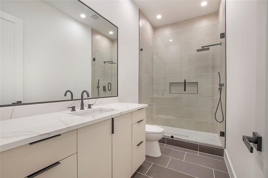 Bathroom with walk in shower, tile patterned flooring, vanity, and toilet