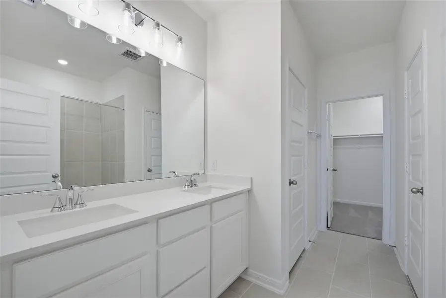 This primary bathroom is definitely move-in ready! Featuring stained cabinets with light countertops, dual vanities, high ceilings, neutral paint, walk-in closet, sleek and modern finishes.