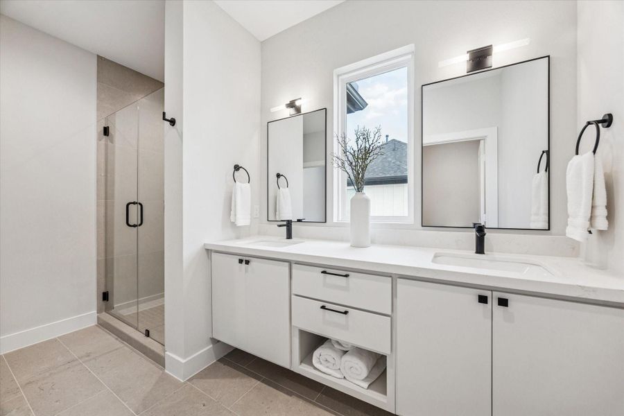 The spa inspired primary bath features a floating vanity with double sinks, ample storage, a glass enclosed shower and a water closet.