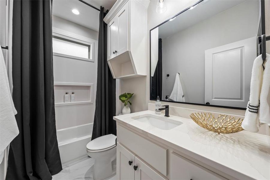 Full bathroom featuring shower / bathtub combination with curtain, vanity, light marble finish flooring, and recessed lighting Full bathroom featuring shower / bathtub combination with curtain, vanity, light marble finish flooring, and recessed lighting