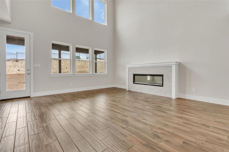 A spacious living room features soaring ceilings, a modern fireplace, and large windows that invite abundant natural light.