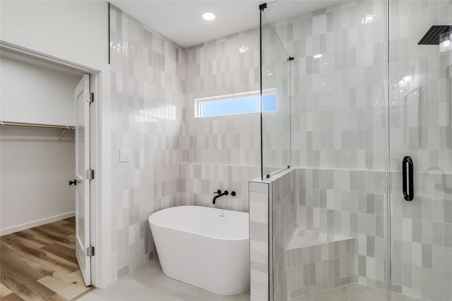 Bathroom featuring a freestanding tub, a spacious closet, recessed lighting, and a stall shower