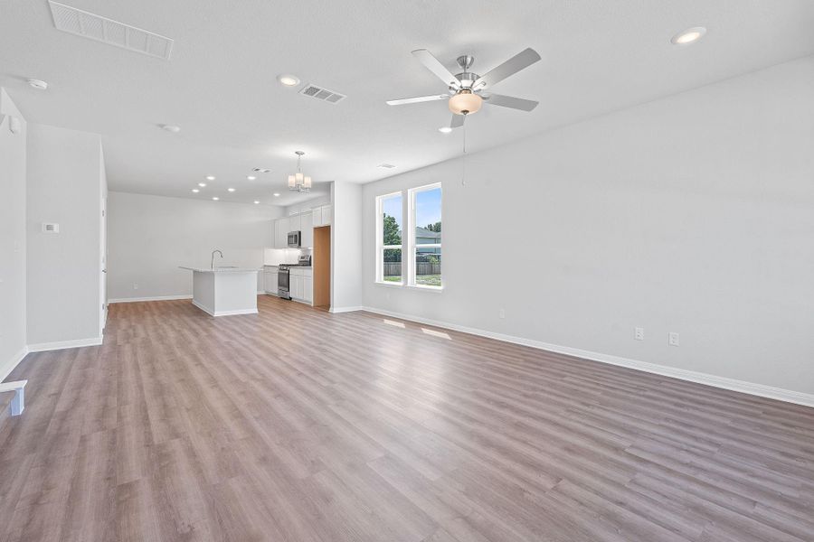Unfurnished living room with light wood finished floors, recessed lighting, a ceiling fan, and a chandelier