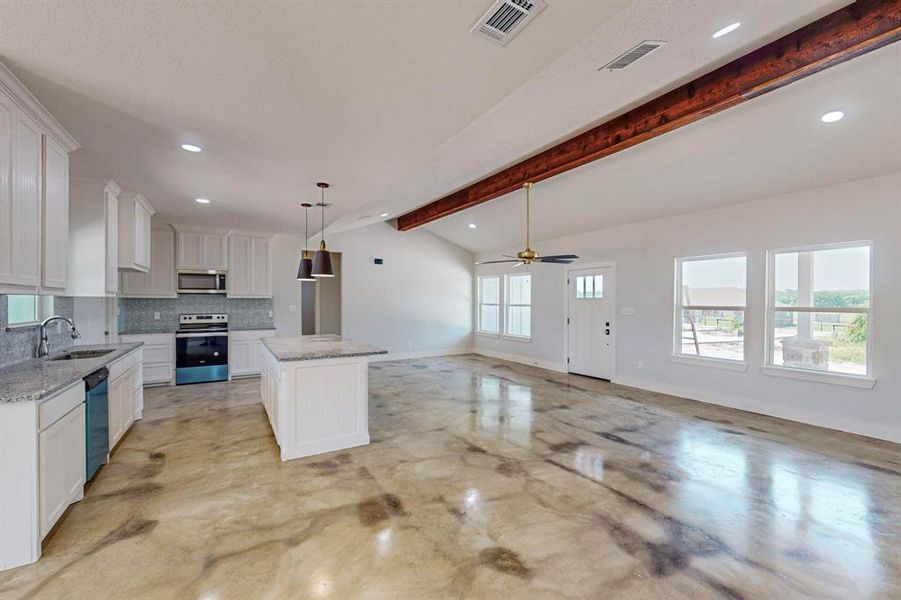 Kitchen featuring white cabinets, sink, a kitchen island, lofted ceiling with beams, and appliances with stainless steel finishes