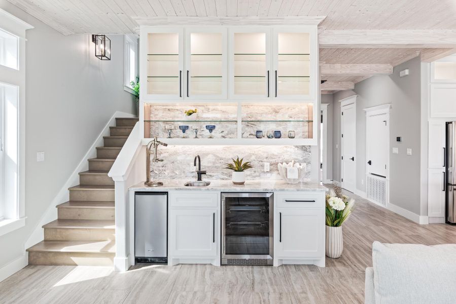 Indoor wet bar featuring beverage cooler, a wood ceiling with exposed beams, stairway, and light wood-style flooring Indoor wet bar featuring beverage cooler, a wood ceiling with exposed beams, stairway, and light wood-style flooring