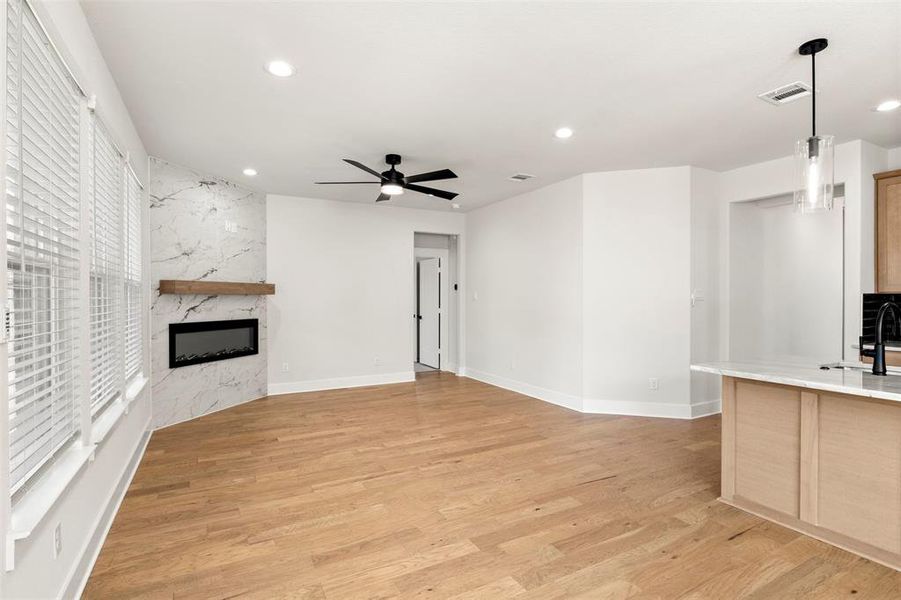 Unfurnished living room featuring a high end fireplace, recessed lighting, light wood finished floors, and a ceiling fan