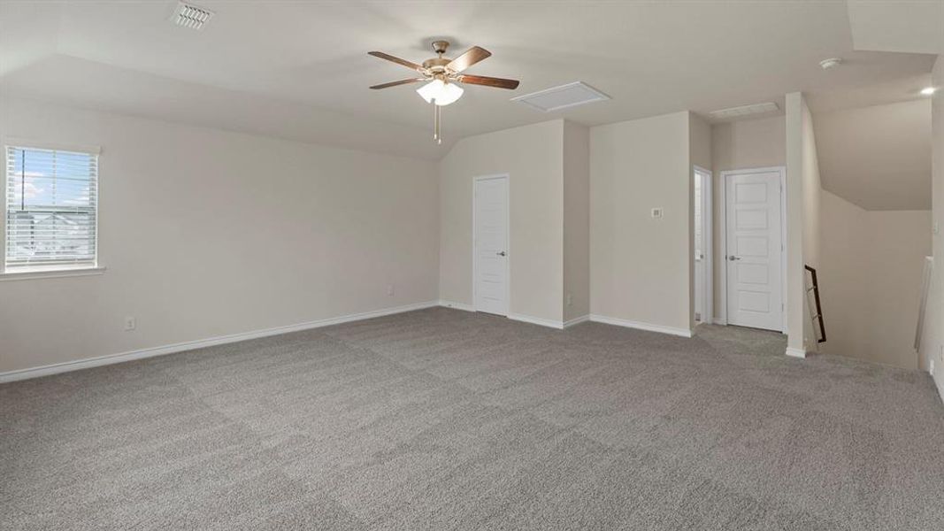 Unfurnished bedroom with light colored carpet, attic access, a ceiling fan, and vaulted ceiling Unfurnished bedroom with light colored carpet, attic access, a ceiling fan, and vaulted ceiling