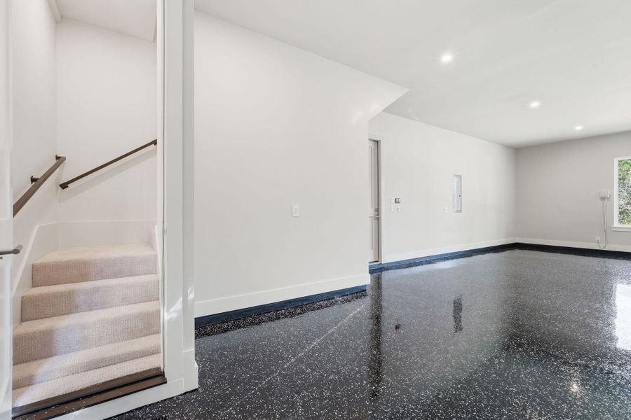 Stairs inside the Texas-size 3 car garage lead to another massive flex space. Would make an excellent long-term guest suite or "man cave."