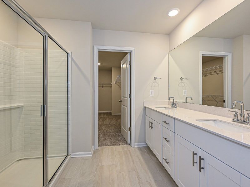The primary bathroom boasts a dual-sink vanity and walk-in shower.