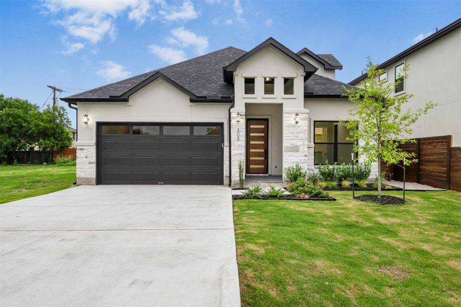 Contemporary home featuring stucco and stone siding, an attached garage, concrete driveway, and a shingled roof. Contemporary home featuring stucco and stone siding, an attached garage, concrete driveway, and a shingled roof.