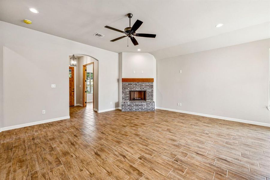 Unfurnished living room featuring ceiling fan, light wood-type flooring, and a fireplace