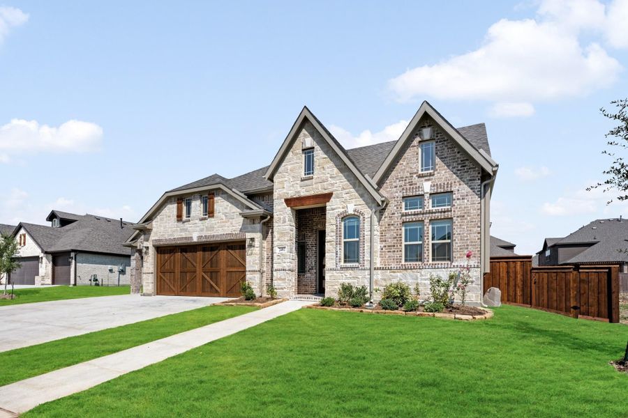 Two-story brick and stone home with wood garage doors, arched entry, and green front lawn. Two-story brick and stone home with wood garage doors, arched entry, and green front lawn.