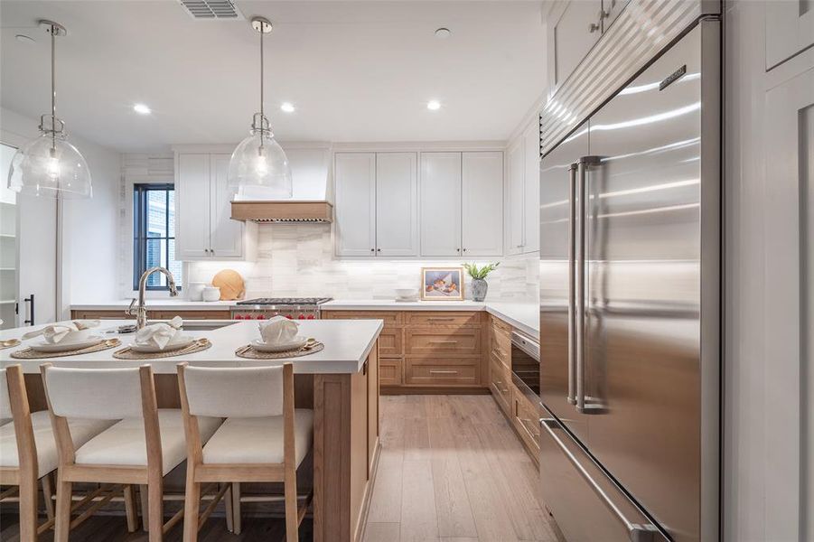 Kitchen featuring hanging light fixtures, appliances with stainless steel finishes, a center island, and white cabinets