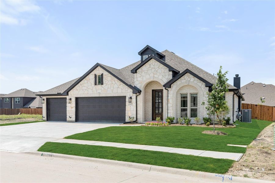 Single-story home with stone exterior, arched entry, three-car garage, and green front lawn