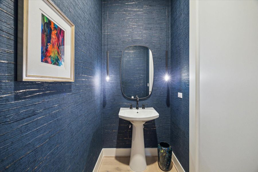 Half bath with luxurious wallcovering and pendant lighting.