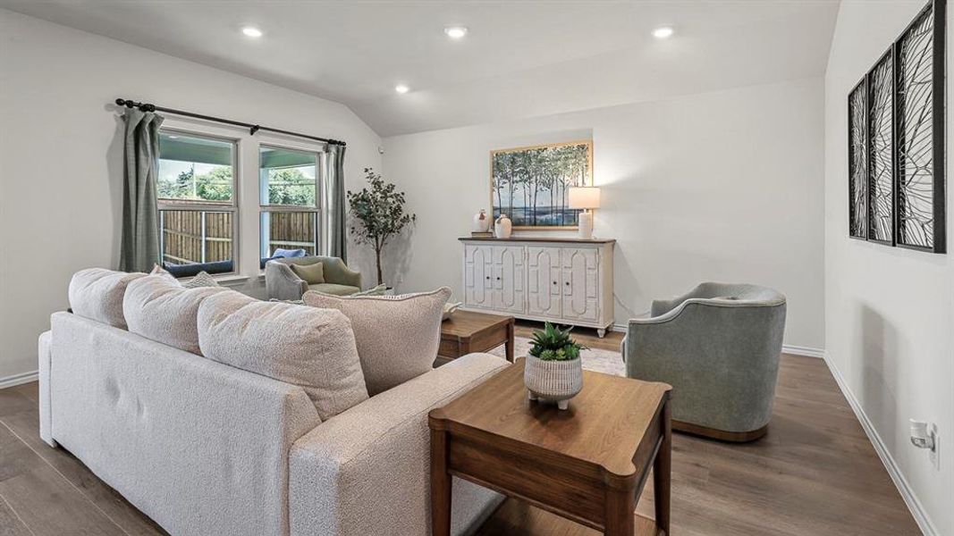 Living area featuring light wood-look flooring, recessed lighting, and windows with curtains providing natural light
