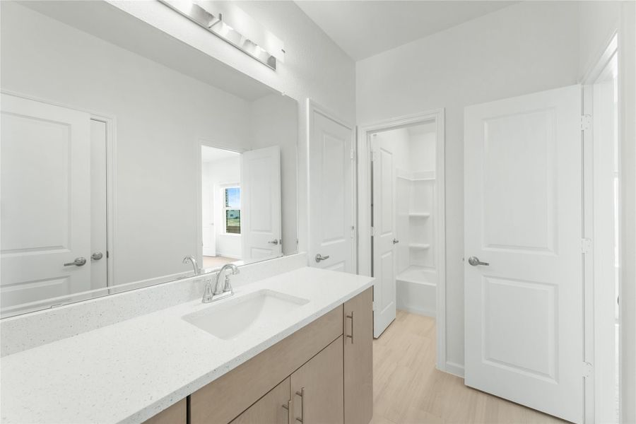 Bathroom with single vanity, white quartz countertop, large mirror, and separate tub-shower room visible through open door
