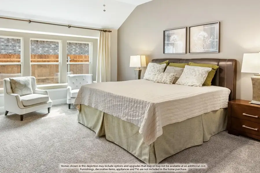Bedroom with vaulted ceiling, king bed, carpet flooring, and two accent chairs near large windows