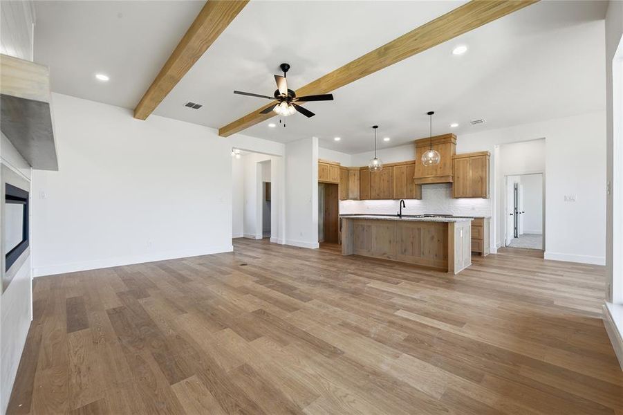 Unfurnished living room with a ceiling fan, recessed lighting, light wood-style flooring, and beamed ceiling Unfurnished living room with a ceiling fan, recessed lighting, light wood-style flooring, and beamed ceiling