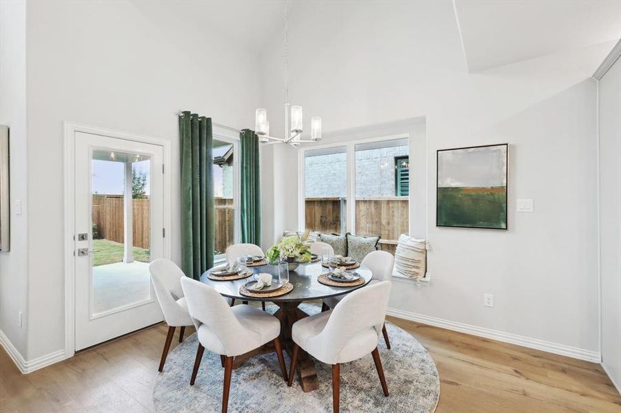 Dining area featuring suspended lighting, light wood-style floors, and a high ceiling