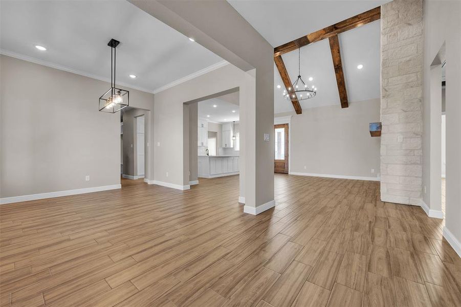 Unfurnished living room with recessed lighting, light wood-style flooring, beamed ceiling, high vaulted ceiling, and a chandelier Unfurnished living room with recessed lighting, light wood-style flooring, beamed ceiling, high vaulted ceiling, and a chandelier