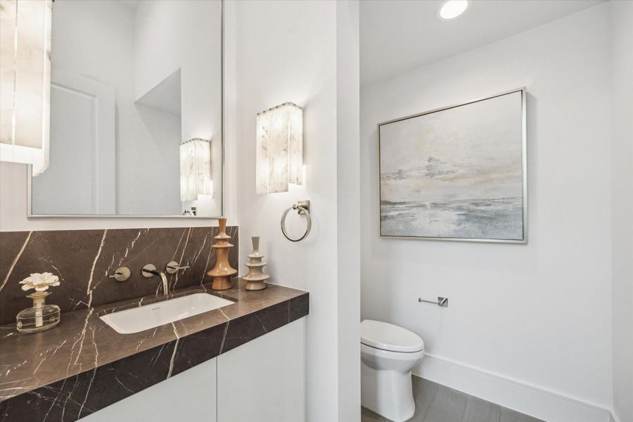 First floor powder features Leathered Piatra Gray Marble counter and backsplash, Kallista luxury fixtures and undermount sink, and additional storage. First floor powder features Leathered Piatra Gray Marble counter and backsplash, Kallista luxury fixtures and undermount sink, and additional storage.