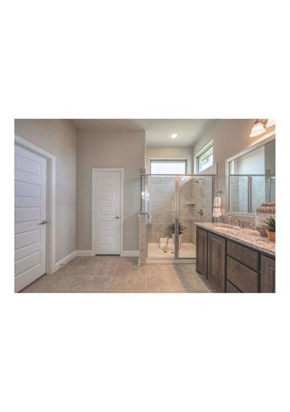 Bathroom featuring a shower with door, tile patterned flooring, and vanity